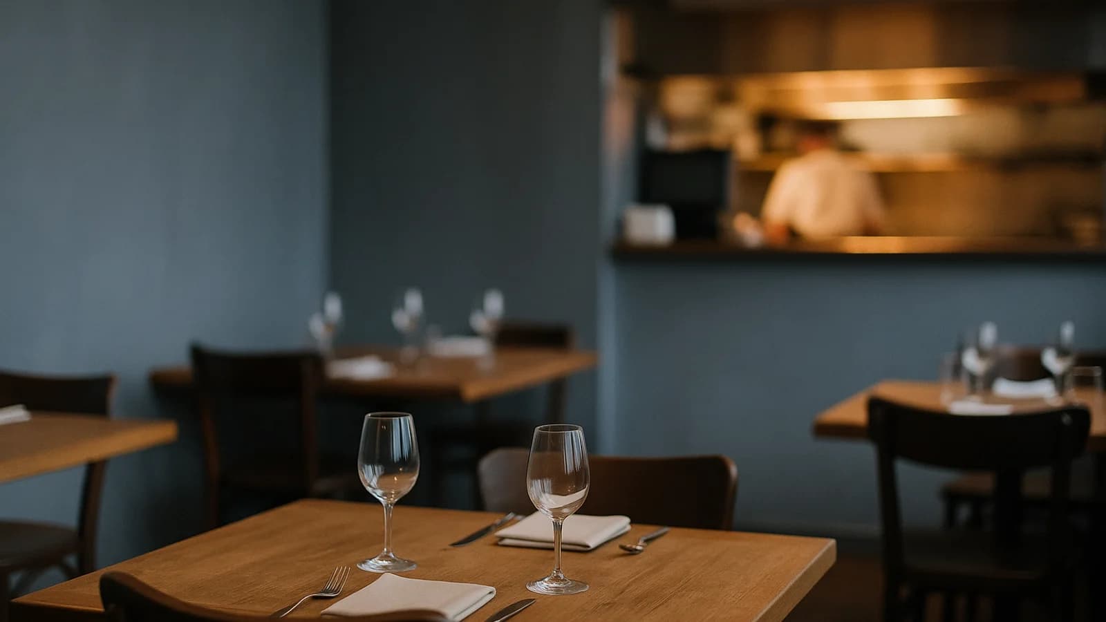 A restaurant pass at the start of service: plated dishes under warm lights, a tablet showing order tickets, and a server's hands reaching for two plates.